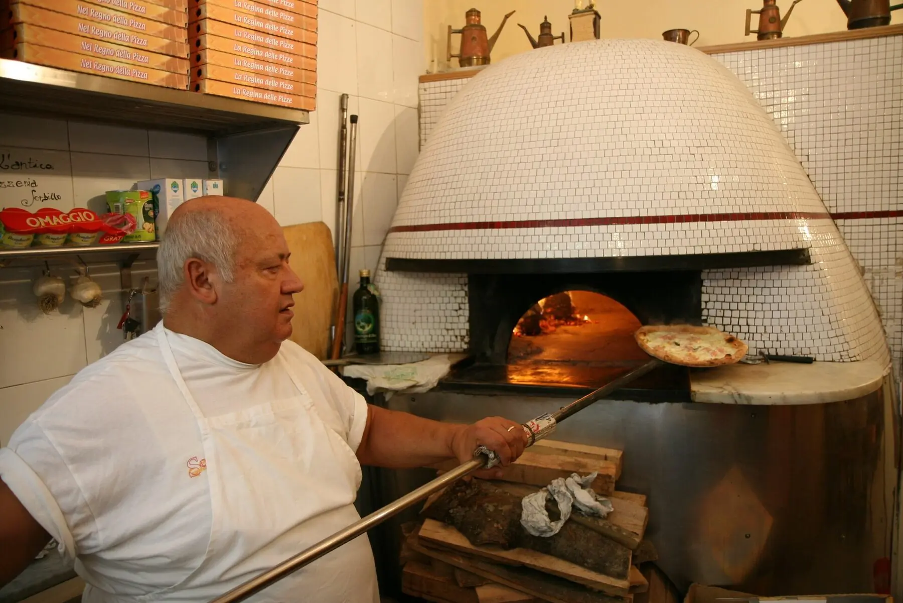 A chef’s hands presenting a finished pizza on the counter